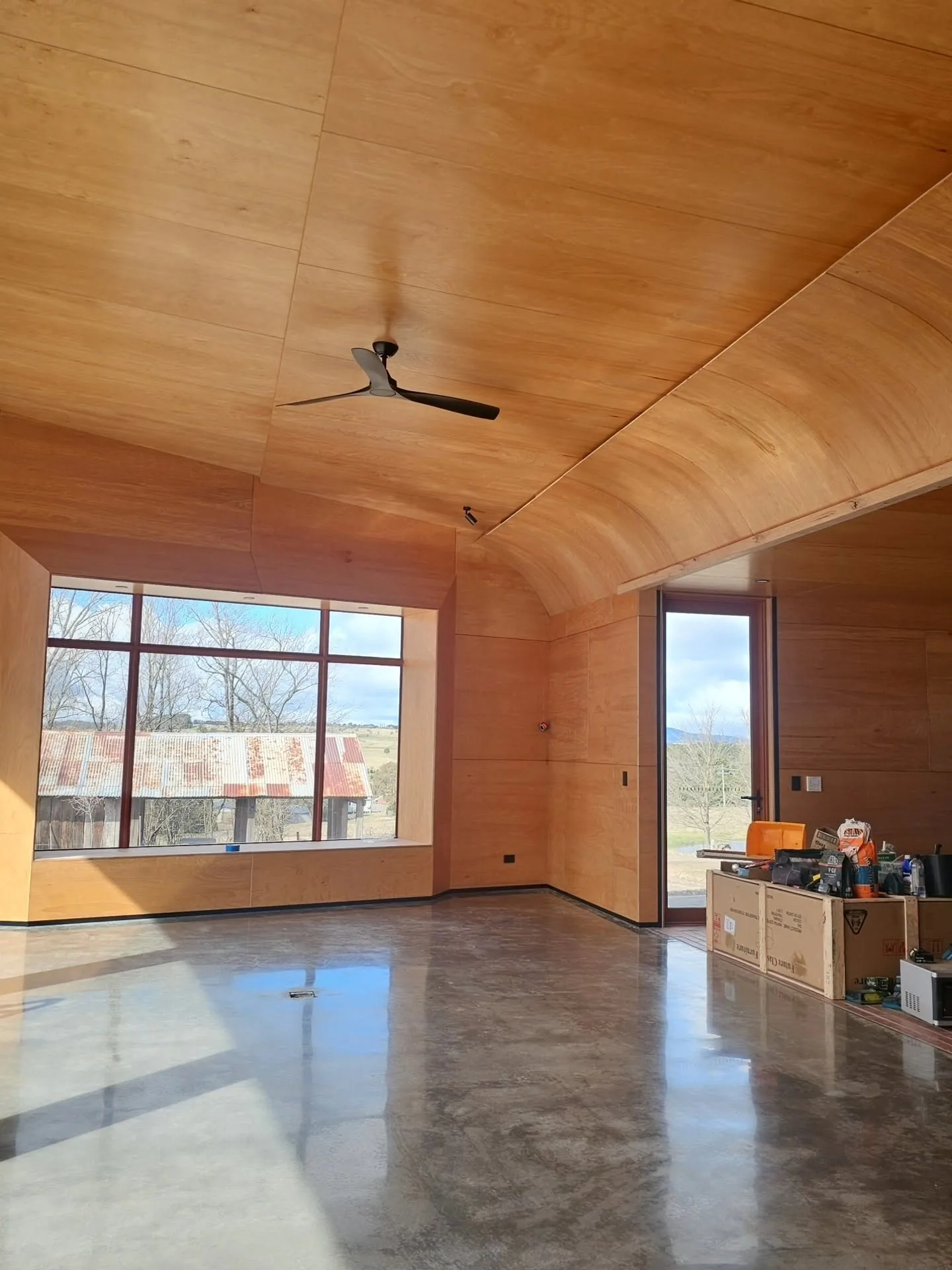 Polished concrete in a timber-lined room with a window onto open country